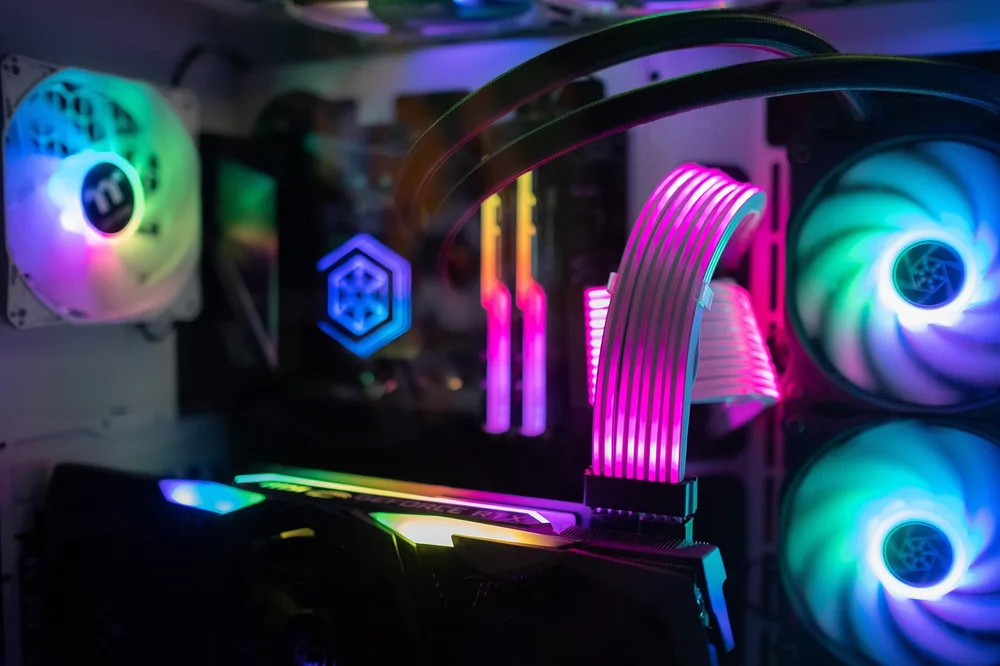 A gaming desk glowing with warm amber light behind the monitor