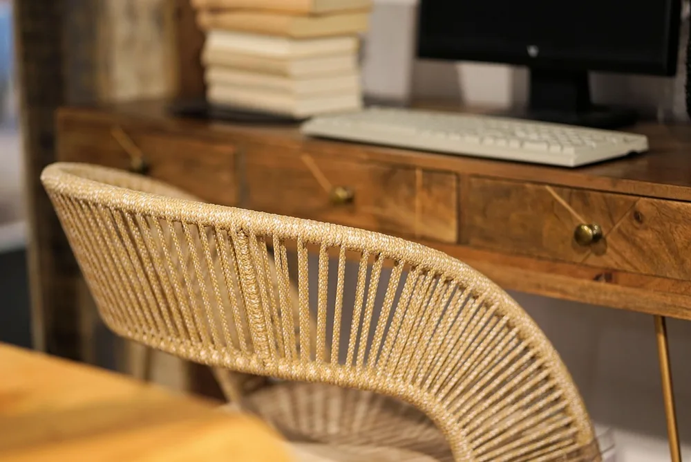 A slim desk drawer half open with pens and chargers sorted in small trays